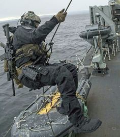 a man sitting on top of a boat in the ocean next to another person holding a pole