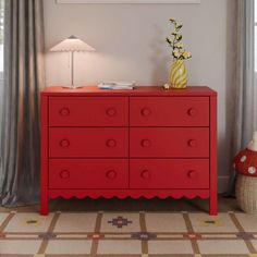 a red dresser in a room with a lamp and pictures on the wall behind it