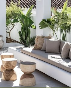 an outdoor living area with couches, tables and potted plants