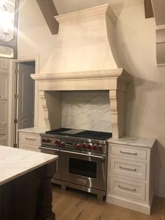 a stove top oven sitting inside of a kitchen next to white cupboards and drawers