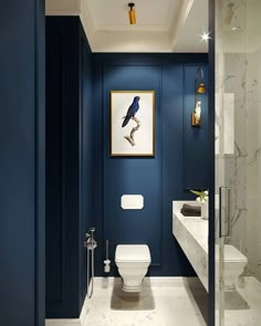 a blue bathroom with a white toilet and sink in the corner, along with a painting on the wall