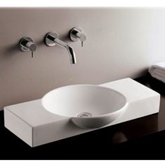 a white sink sitting on top of a counter next to a wall mounted faucet