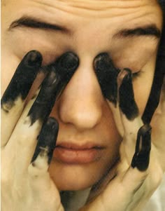 a woman holding her hands up to her face with black and white cats on them