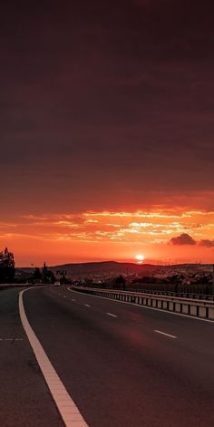 the sun is setting on an empty highway