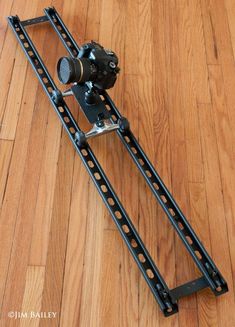 a close up of a camera on a wooden floor with a tripod attached to it