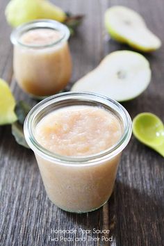 two small jars filled with food sitting on top of a wooden table next to sliced apples