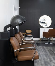 a hair salon with brown chairs and black walls