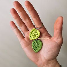 a green leaf shaped keychain hanging from a ring on someone's hand