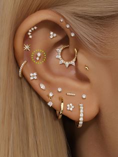 an ear with multiple piercings and stars on the middle one is gold, while the other is white