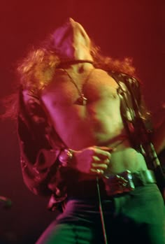 a shirtless man on stage with his back turned to the camera and holding a microphone