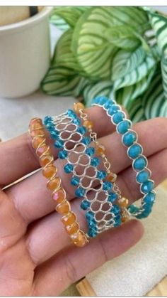 a person is holding three different bracelets in their hand, one with blue beads and the other with orange beads