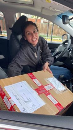 a woman sitting in the back seat of a car holding a box