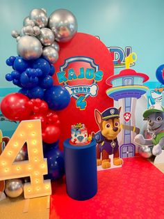 a birthday party with balloons and decorations on the table, including paw patrol cake toppers