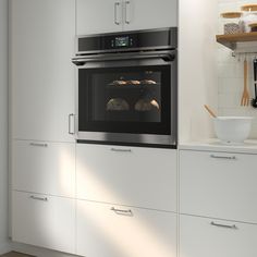 a white kitchen with an oven built into the wall