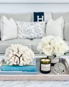 a coffee table with flowers and candles on it in front of a couch that has pillows