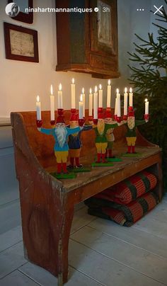 a wooden bench with candles on it in front of a christmas tree and other decorations