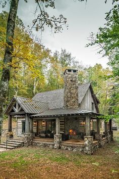 a log cabin with a stone chimney in the woods