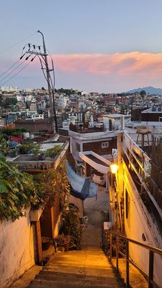 an alleyway with stairs leading up to the top floor and buildings in the background