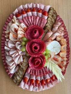 a platter filled with meats, cheeses and flowers on top of a wooden table