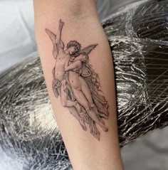 a tattoo on the arm of a woman with two cherubs holding each other