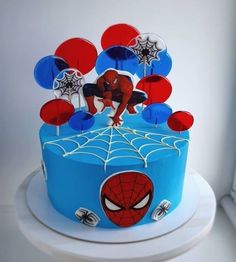 a spiderman themed birthday cake with red, white and blue decorations on the top