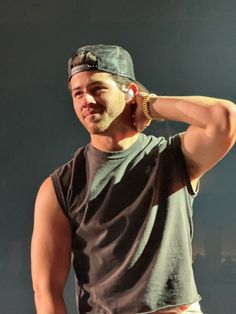 a male in a black and gray shirt is holding his hands to his ears while standing on stage