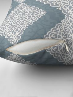 a blue and white pillow with an intricate design on it's side, along with a zippered closure