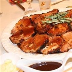 a white plate topped with meat covered in sauces and garnished with rosemary