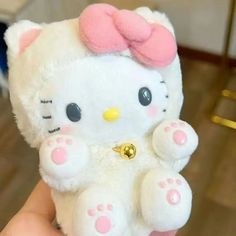 a white hello kitty stuffed animal with pink ears and paws on it's chest