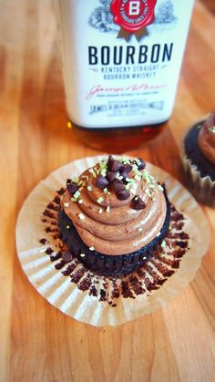 two cupcakes with chocolate frosting and sprinkles on a wooden table