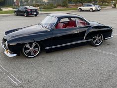 an old black car parked in a parking lot