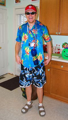 a man standing in the middle of a kitchen wearing sunglasses and a blue shirt with flowers on it