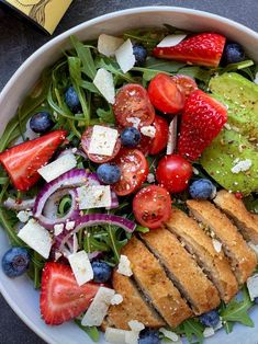 a salad with chicken, tomatoes, blueberries and avocado