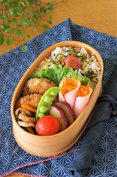 a wooden bowl filled with lots of different types of food on top of a blue cloth