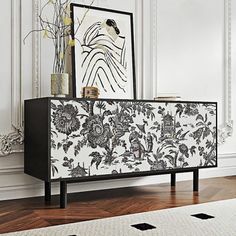 a black and white cabinet with flowers on it next to a rug in a room