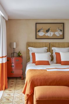 an orange and white bed in a bedroom with two nightstands next to each other