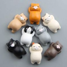 there are many small cat figurines on the table in different colors and sizes