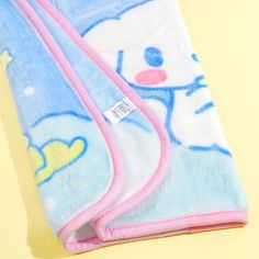 two blue and pink hello kitty towels laying next to each other on a yellow surface