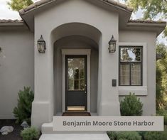 the front entrance to a house with a black door and two lights on each side