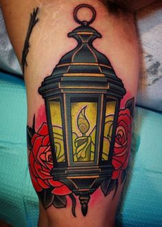 a tattoo with a lantern and roses on it