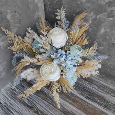 a bouquet of flowers sitting on top of a wooden table next to a gray wall