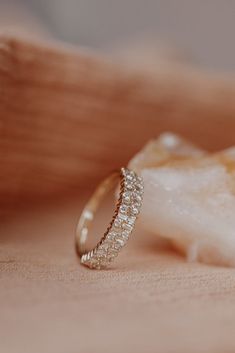 a diamond ring sitting on top of a piece of white rock next to a sea shell