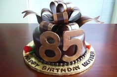 a chocolate birthday cake with the number 85 on it's side and flowers in the middle