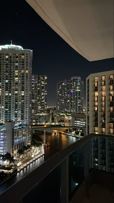 the city skyline is lit up at night with skyscrapers in the foreground and water below