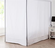 a bed with a white canopy and two nightstands next to it in a room