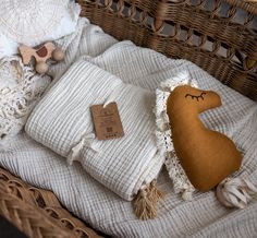 a stuffed animal laying on top of a blanket next to pillows and blankets in a wicker basket