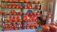 an assortment of orange pots and pans on shelves