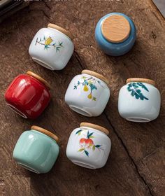 six ceramic jars with painted flowers on them sitting on a wooden table next to a knife