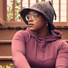 a woman wearing glasses and a hat sitting on steps