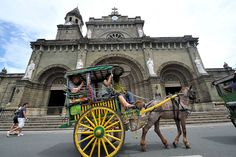 a horse drawn carriage in front of an old building with people riding on the back